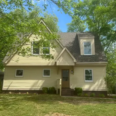 Two-story house with pale yellow siding and white-trimmed windows