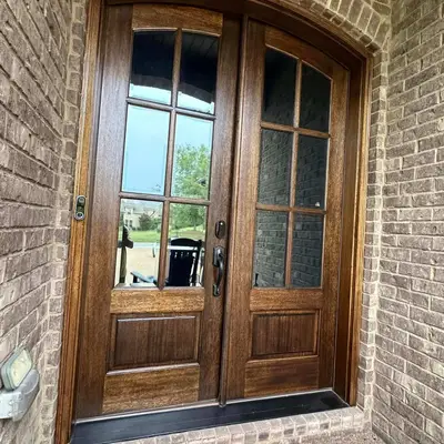 Dark stained wood double front doors set in a brick archway