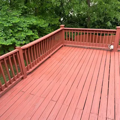 Reddish-brown stained wood deck with matching railing, surrounded by trees