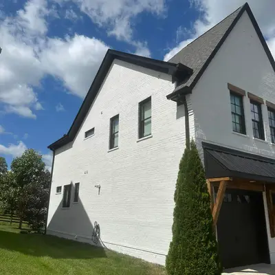 White-painted brick house with dark trim and a standing-seam awning