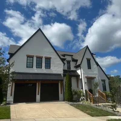 White brick home with dark garage doors, painted by Mr. Wu's Painting