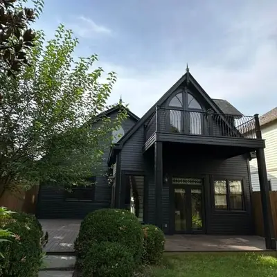 Dark navy house with board-and-batten siding and an iron-railed balcony