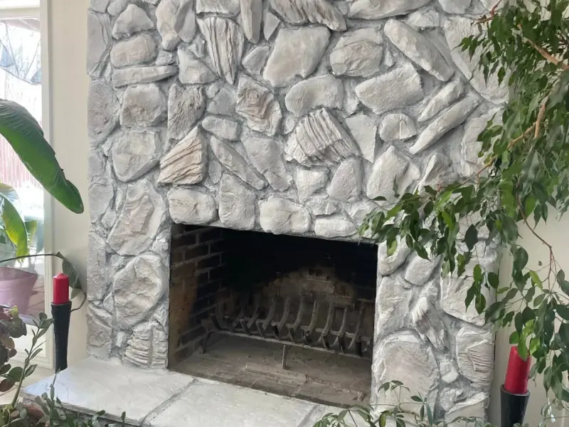 Whitewashed stone fireplace surrounded by potted plants and candle holders