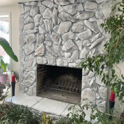 Whitewashed stone fireplace surrounded by potted plants and candle holders