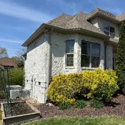 White-painted brick house with a dormer window and flowering shrub