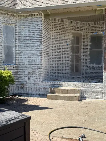 Brick exterior being limewashed by Mr. Wu's Painting, windows taped off