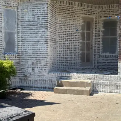 Brick exterior being limewashed by Mr. Wu's Painting, windows taped off