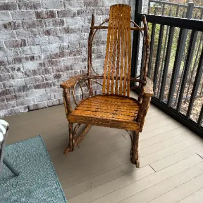 Wood rocking chair on a covered porch with a brick wall