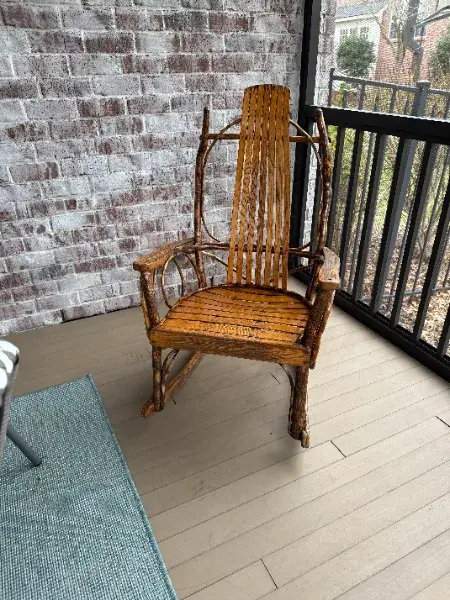 Wood rocking chair on a covered porch with a brick wall