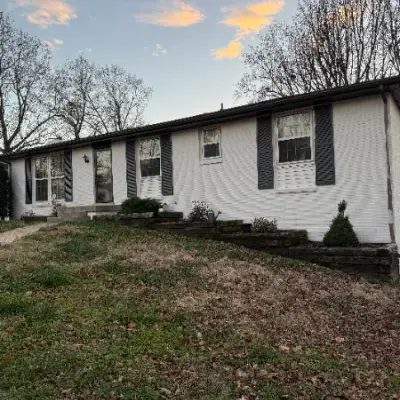 White ranch house with dark shutters at dusk