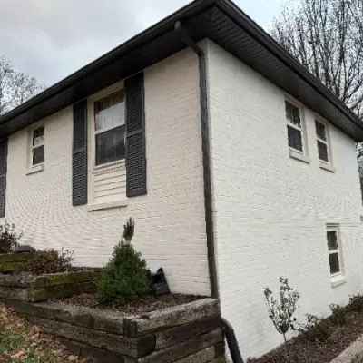 White-painted brick house with dark shutters and gutters
