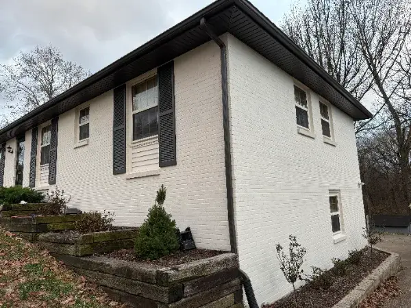 White-painted brick house with dark shutters and gutters