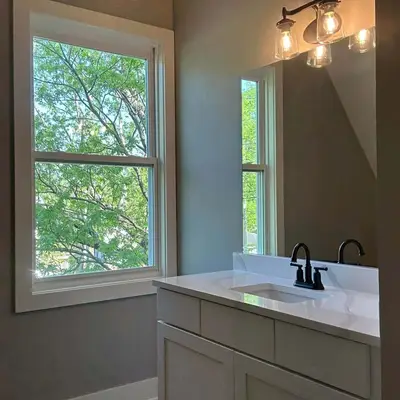 Bathroom with taupe walls, a white vanity cabinet, and black fixtures