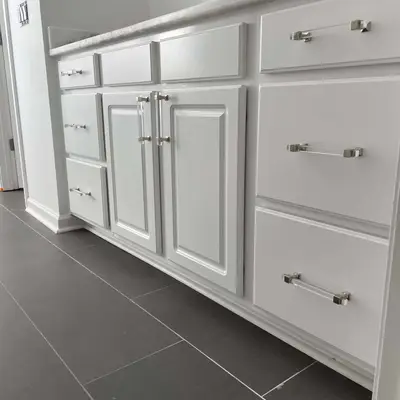 White bathroom vanity cabinets with paneled doors and polished chrome pulls