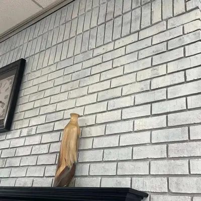 Whitewashed brick fireplace topped with a dark wood mantel shelf