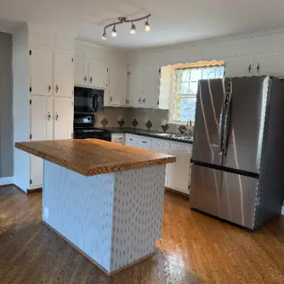 Kitchen island with a wood countertop and white textured painted base