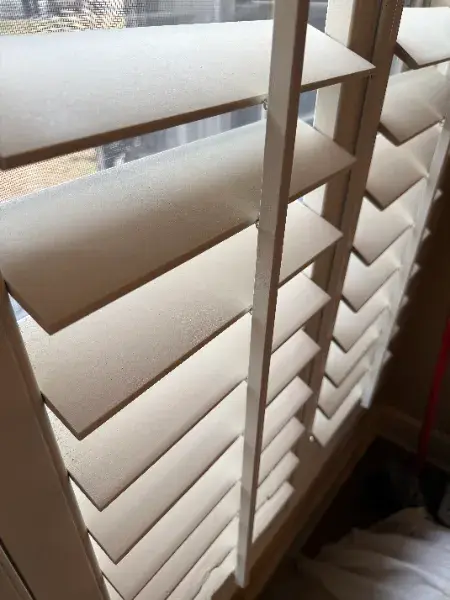 Close-up detail of white-painted plantation shutters on a window