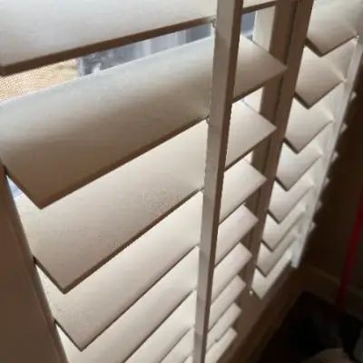 Close-up detail of white-painted plantation shutters on a window